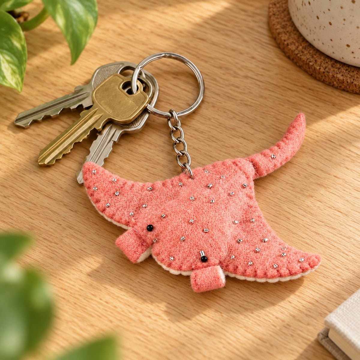 Rosie the Ray, a pink felt manta ray with tiny clear beads, little black eyes and a long tail, hangs beside pink Christmas decorations.