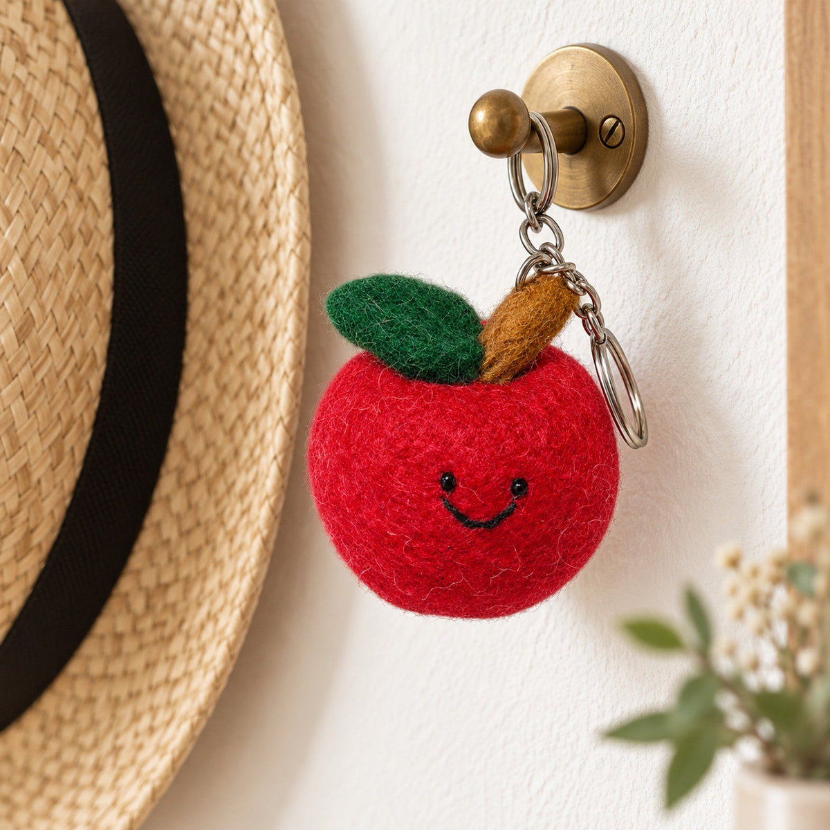 Big Red Apple, a round red felt apple with a dark green leaf and a smiling face, beside a Christmas tree branch.