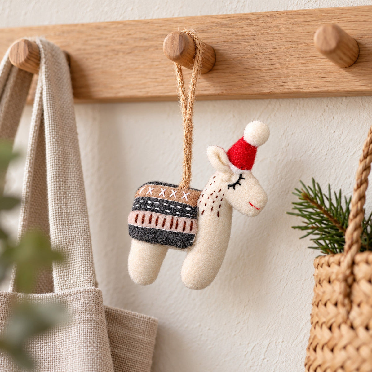Alfie the Alpaca, a white felt hanging ornament with sleepy stitched eyes and a red Santa hat, beside a named Advent calendar gift note.