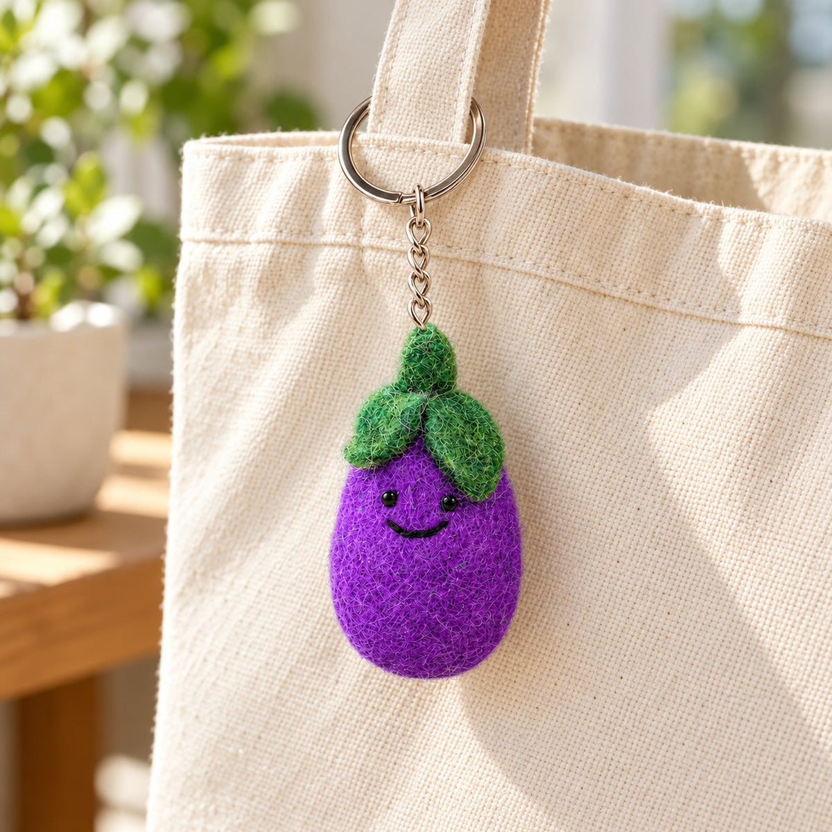 Aubrey Aubergine, a purple felt aubergine keychain with a green cap and a smiling face.