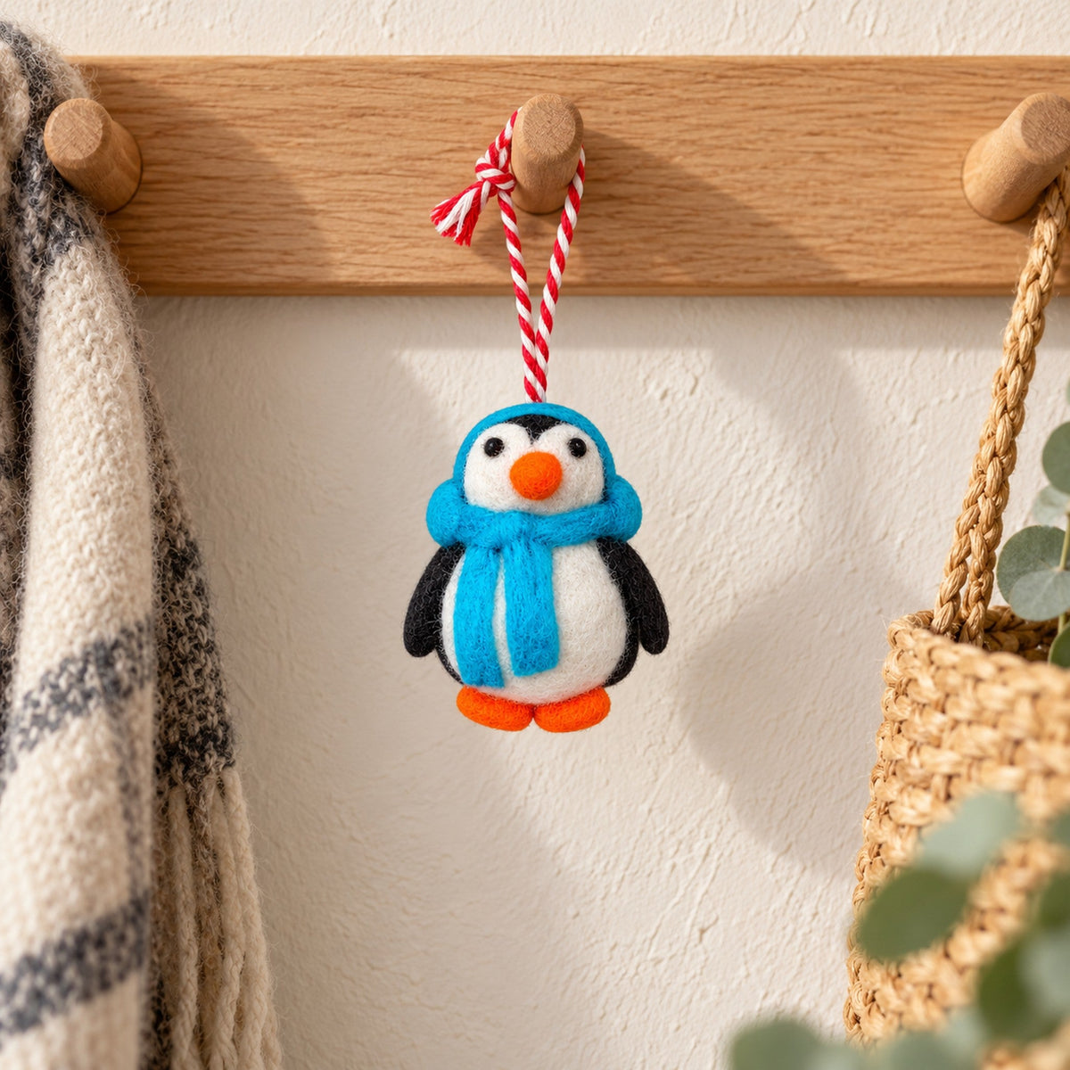 Blue Scarf Penguin, a black-and-white felt ornament with an orange beak, blue scarf and matching ear warmers, beside four numbered Advent parcels.