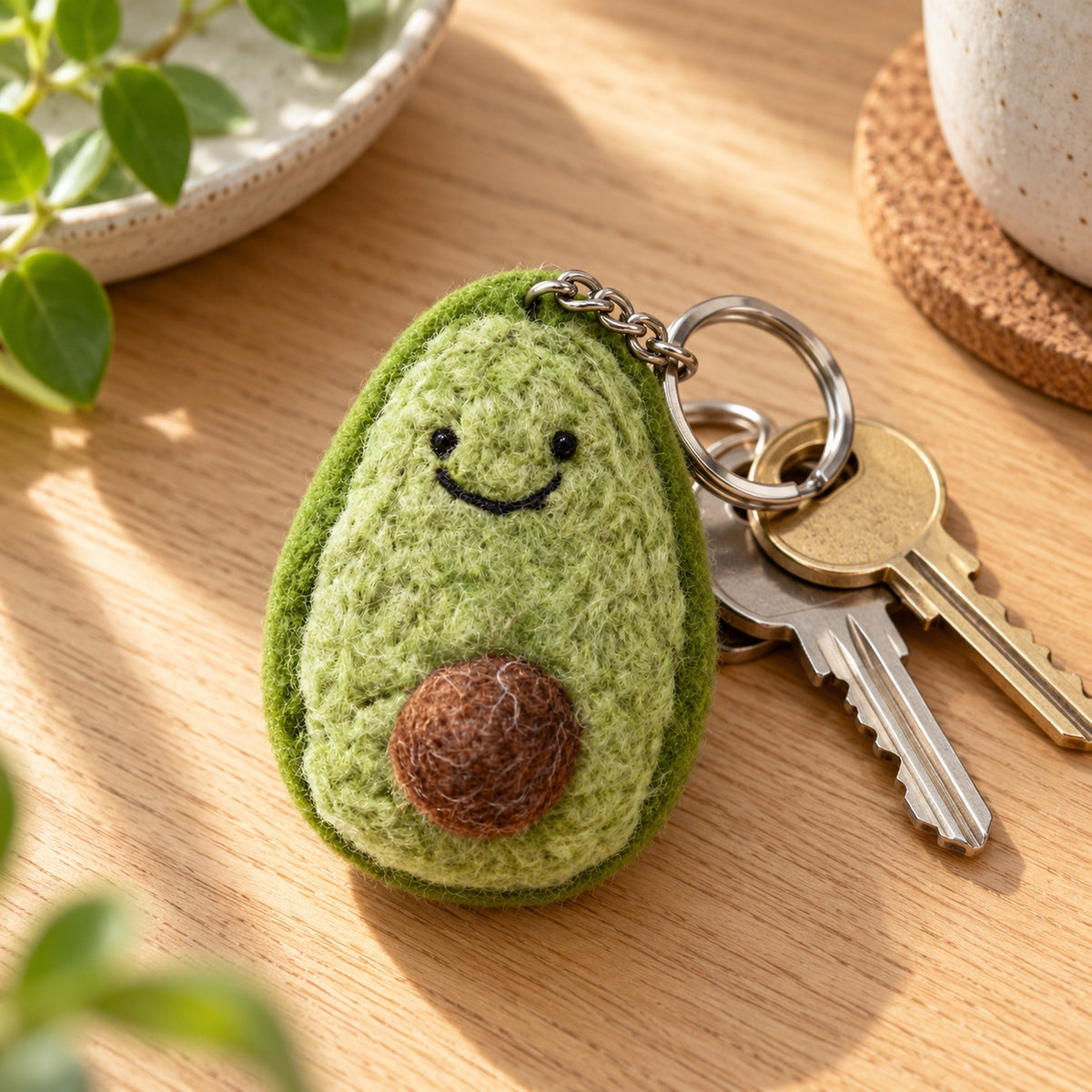 Avery Avocado felt keychain showing a smiling green avocado half with a lighter green middle and a round brown stone.